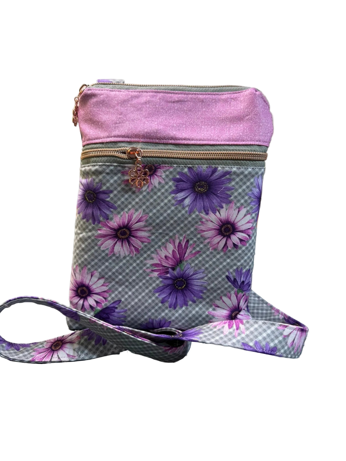 A small crossbody bag with a lavender purple top flap and a gray gingham body printed with purple and pink daisy flowers. The bag has a matching floral and gingham strap.