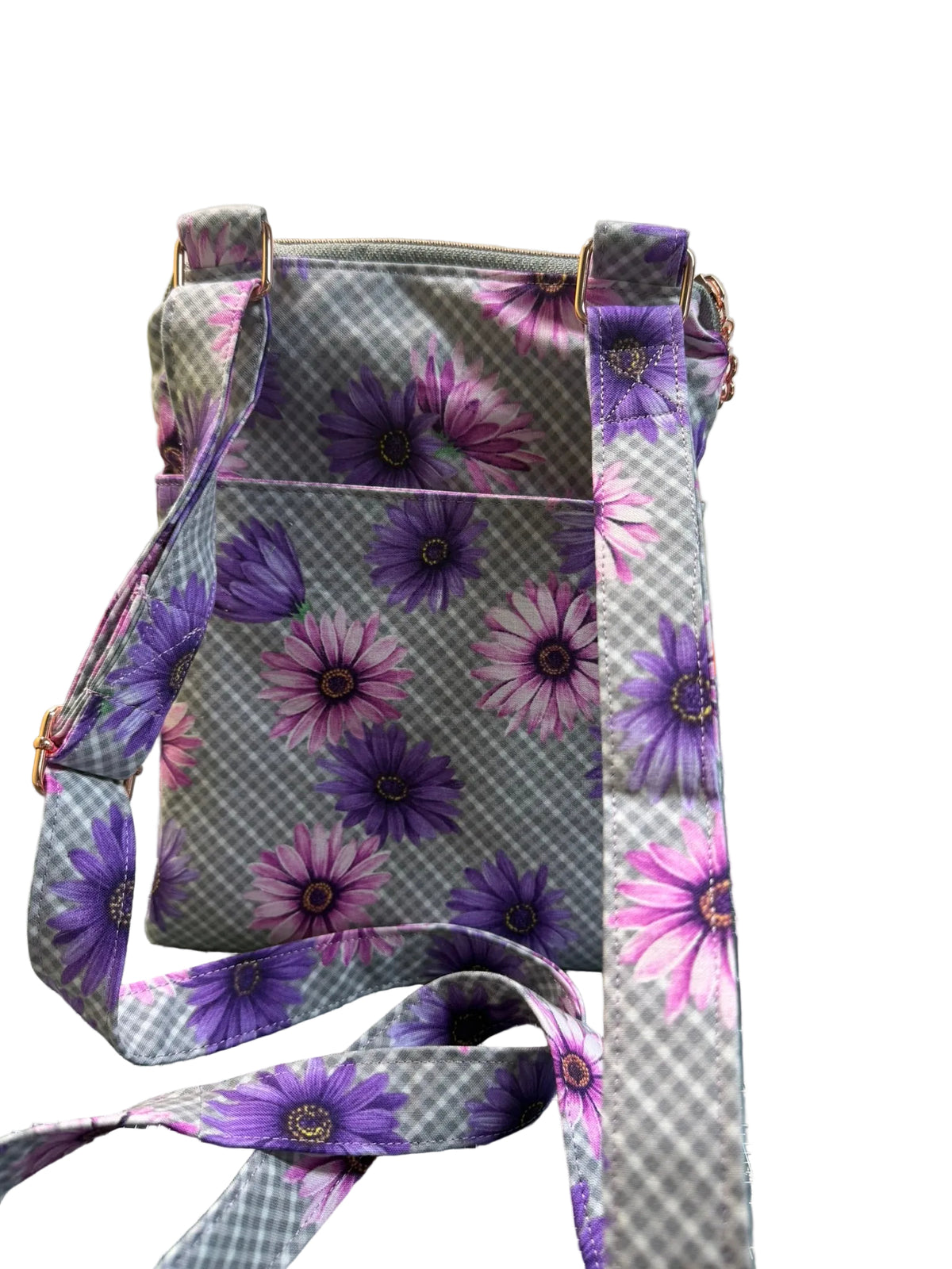 A fabric crossbody bag with a purple and pink daisy floral print over a gray and white gingham background.