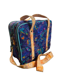 A quilted fabric briefcase with a colorful peacock pattern in purple, blue, and orange, featuring orange handles and a matching shoulder strap.