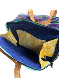 A quilted fabric bag with a multicolor patterned exterior, a bright blue interior, and yellow patterned fabric lining.