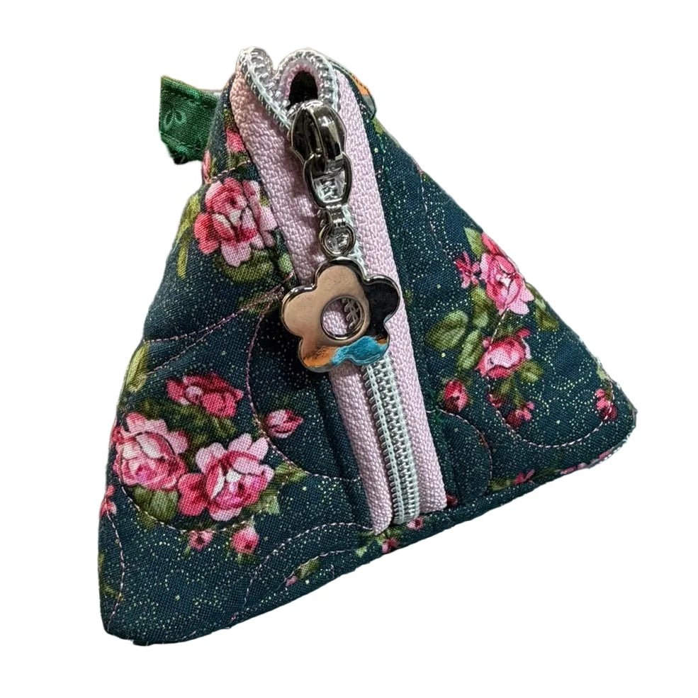 A handmade triangular fabric pouch with a dark blue floral print, pink roses, and a light pink zipper.