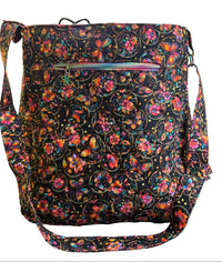 A black fabric shoulder bag with a colorful floral and butterfly pattern, featuring a back zippered pocket with a holographic zipper pull.