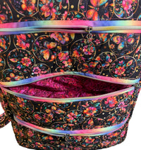 A close-up of a fabric zippered pouch or organizer with a black background, colorful butterfly and floral print, and iridescent rainbow zipper trim.