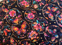 A fabric zippered pouch with a black background and a colorful print of butterflies and flowers inside gold circular frames.