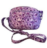 A small crossbody bag with a purple and white floral pattern, featuring a matching fabric strap.