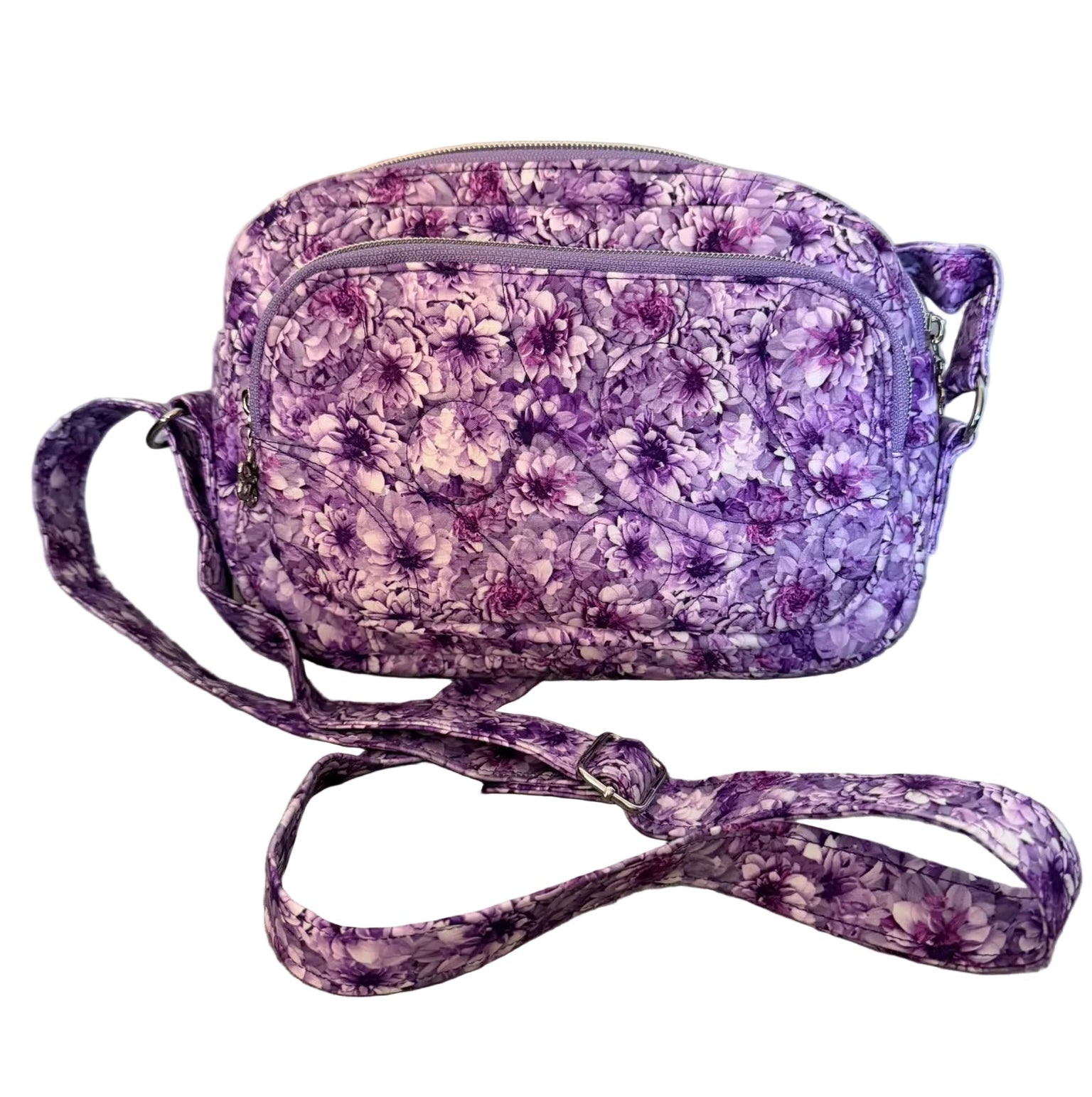 A small crossbody bag with a purple and white floral pattern, featuring a matching fabric strap.
