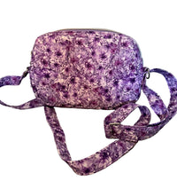 A small crossbody bag with a purple and white floral pattern,.