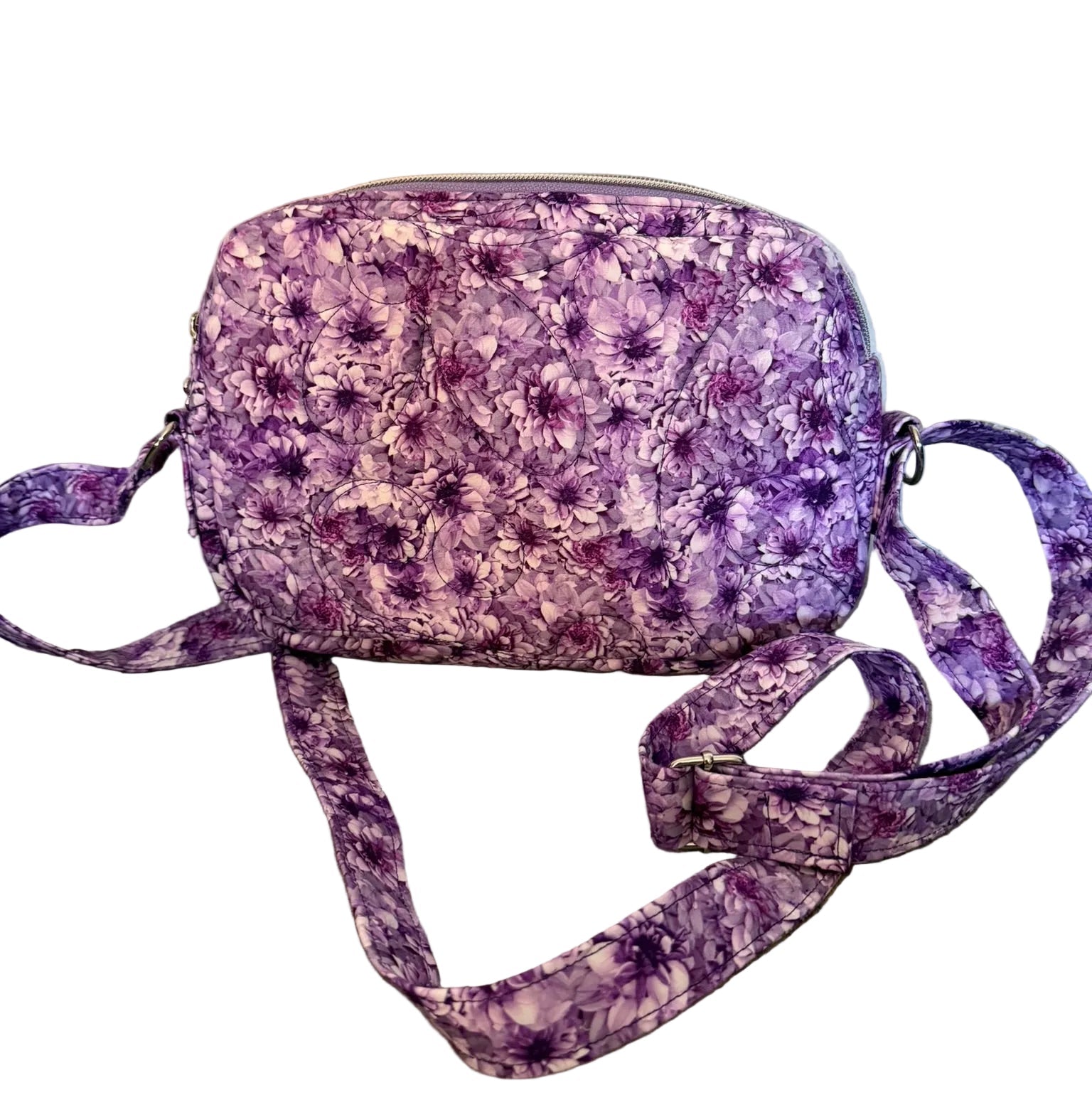 A small crossbody bag with a purple and white floral pattern,.