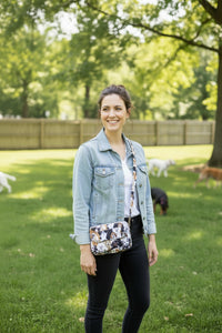 A small purse or wristlet bag with a multicolor print of various dog faces, shown with its matching fabric strap resting in front, 