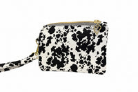 A small black and white cow print pouch bag with gold zipper and hardware, 