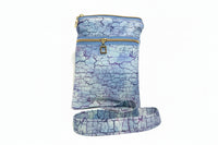 A fabric crossbody bag with a blue and purple crackle pattern, featuring gold zippers and a matching adjustable shoulder strap,