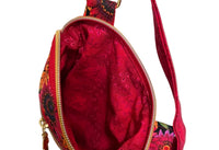 A close-up of a small crossbody bag with a bright red floral patterned fabric, gold-tone zipper, and matching red strap, 