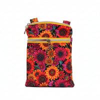 A small crossbody bag with a vibrant sunflower floral print, featuring two gold zippers and a bright pink patterned strap.