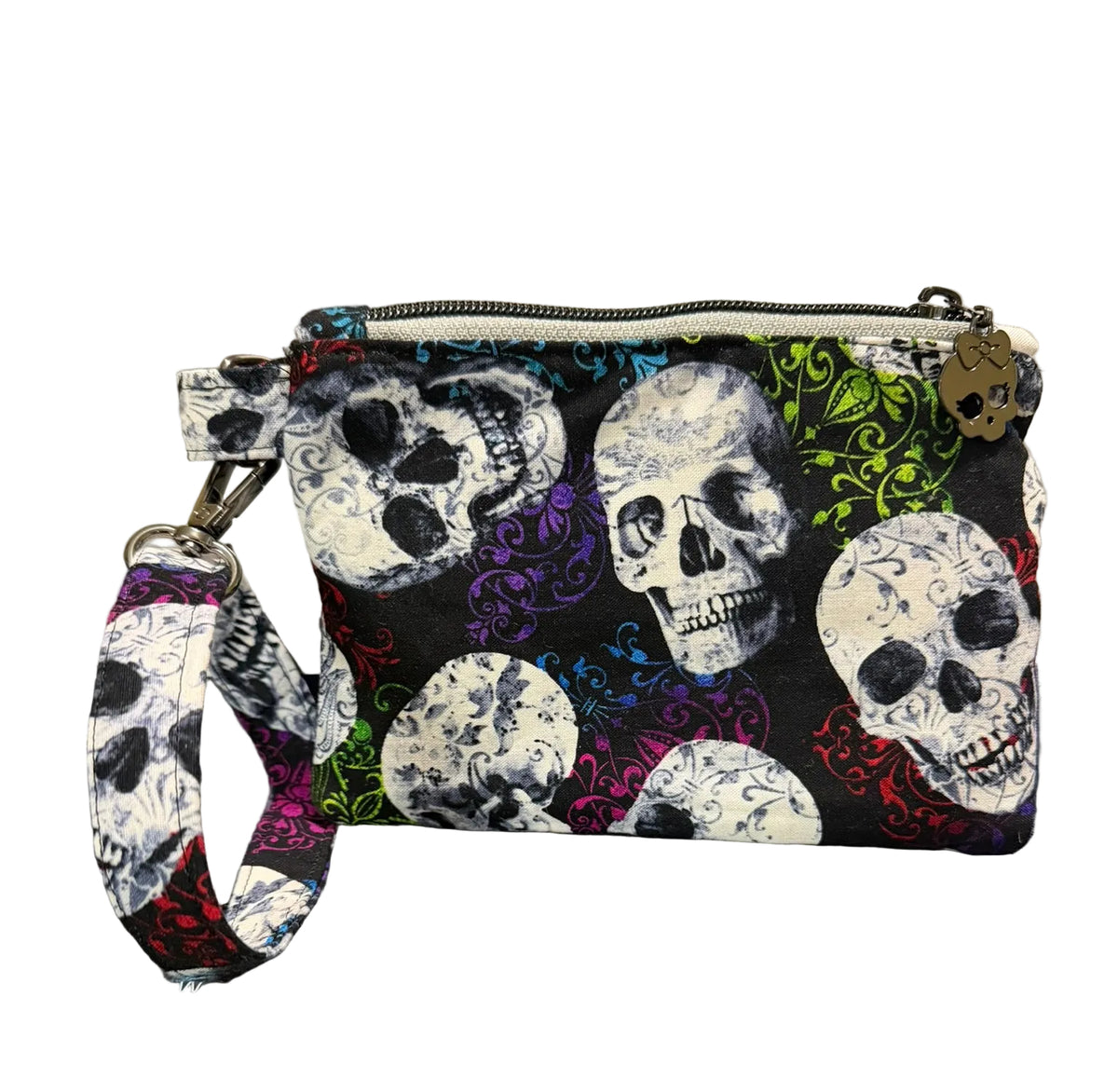 A small zippered wristlet clutch with a colorful skull and floral pattern, resting 